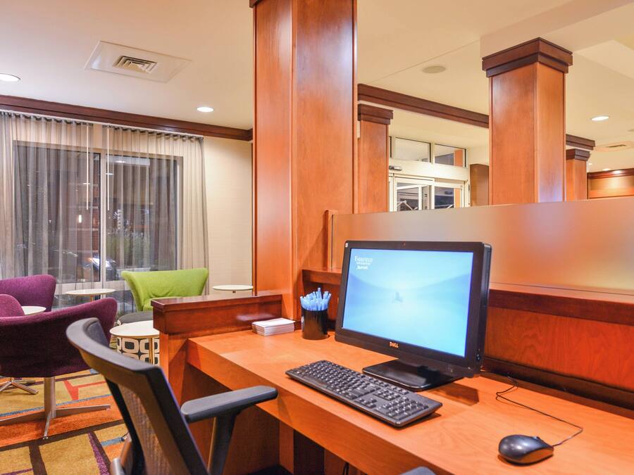 Una habitación de hotel con un escritorio de madera, una computadora y sillas moradas y verdes.