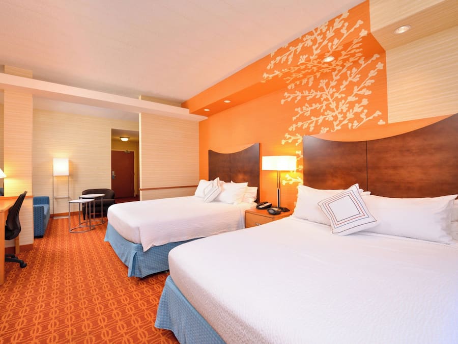 A hotel room with two beds, a desk, and a chair.