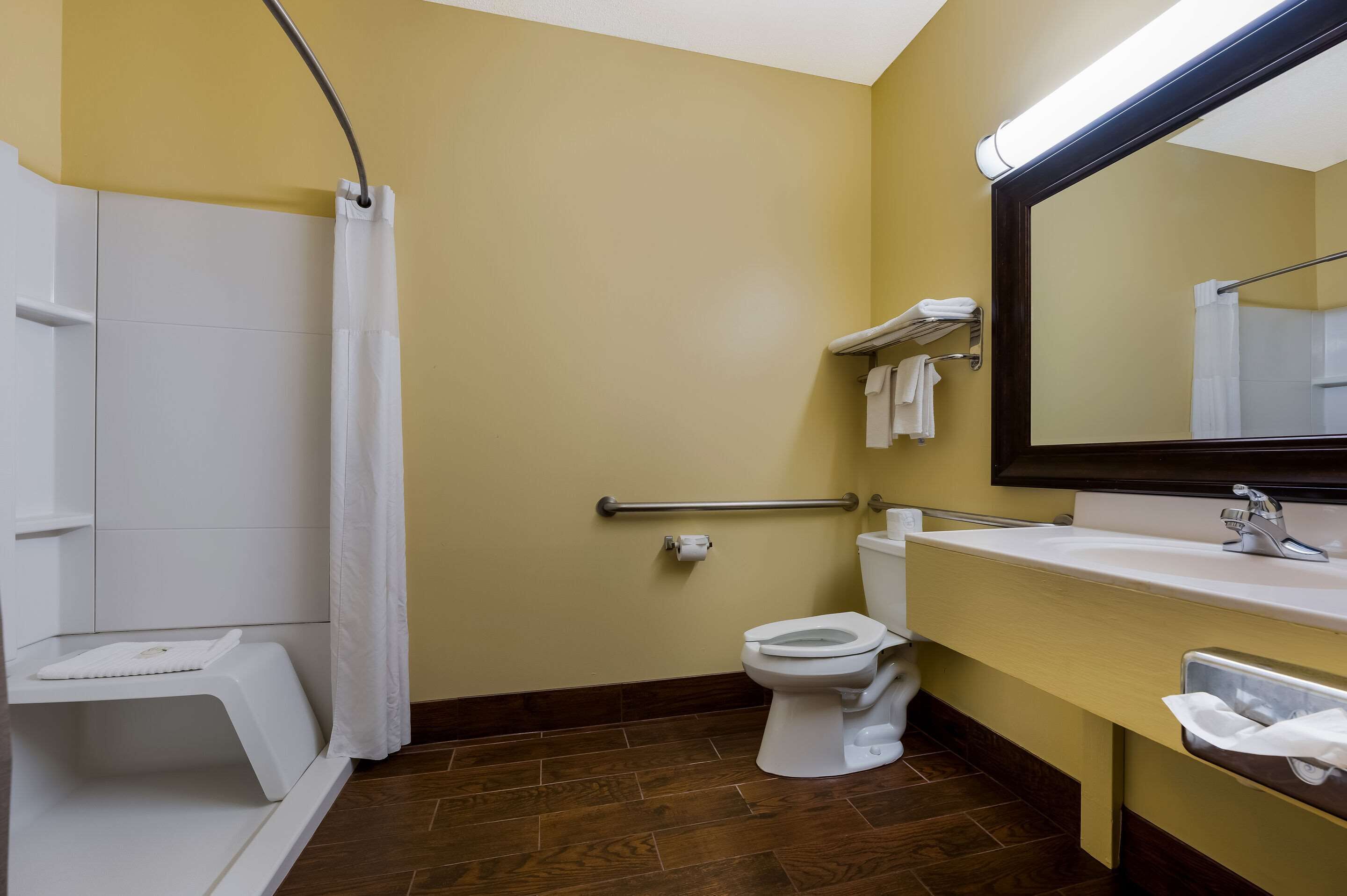 Une salle de bain équipée d’une douche, de toilettes, d’un lavabo et d’un miroir.