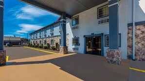 A modern building with a covered entrance, stone pillars, and a clear blue sky. - Quality Inn Fort Payne (Fort Payne)