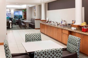 A modern hotel dining area with a kitchen counter, seating, and a view of the outdoors. - Residence Inn by Marriott Chicago Lake Forest/Mettawa (Lake Forest)