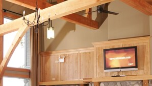 Amplia sala de estar con chimenea de piedra, sofás de cuero y un televisor de pantalla plana sobre la chimenea.