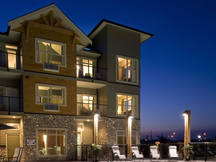 A multi-story hotel with a swimming pool, outdoor seating, and a stone facade.