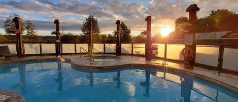 A swimming pool with a sunlit sky and trees in the background.