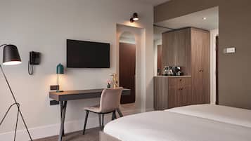 Une chambre d’hôtel moderne équipée d’un lit, d’un bureau avec une chaise, d’un téléviseur à écran plat, d’un téléphone et d’une armoire.
