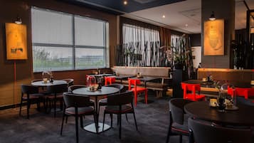 A restaurant with round tables and chairs, large windows, and decorative elements.