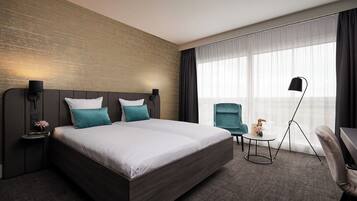 Une chambre d’hôtel moderne, dotée d’un grand lit, d’un bureau, d’une chaise et offrant une vue sur l’extérieur.