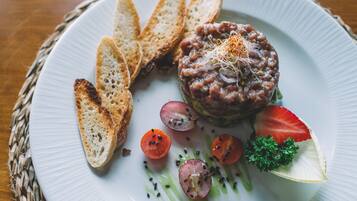 Un plato con un guiso de carne, rebanadas de pan, tomates cherry y una guarnición.