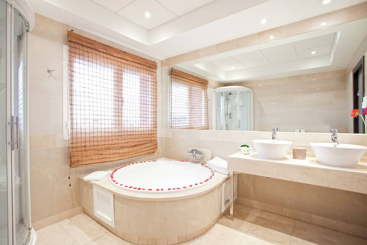 A modern bathroom with a large bathtub, two sinks, a shower, and a mirror.