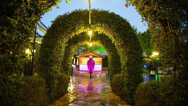 An archway of greenery leading to a building with a purple-lit stage. - Cortijo Chico Málaga Airport (Alhaurin de la Torre)