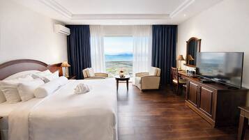 Habitación de hotel con una cama grande, televisión, escritorio y vistas al paisaje.