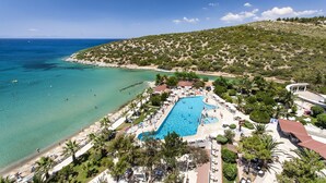A resort with a large swimming pool, beach area, and lush greenery. - Tusan Beach Resort (Kusadasi)