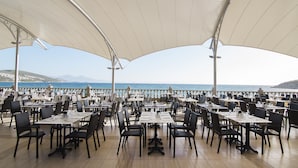 An outdoor dining area with tables and chairs, overlooking a coastal view. - Tusan Beach Resort (Kusadasi)
