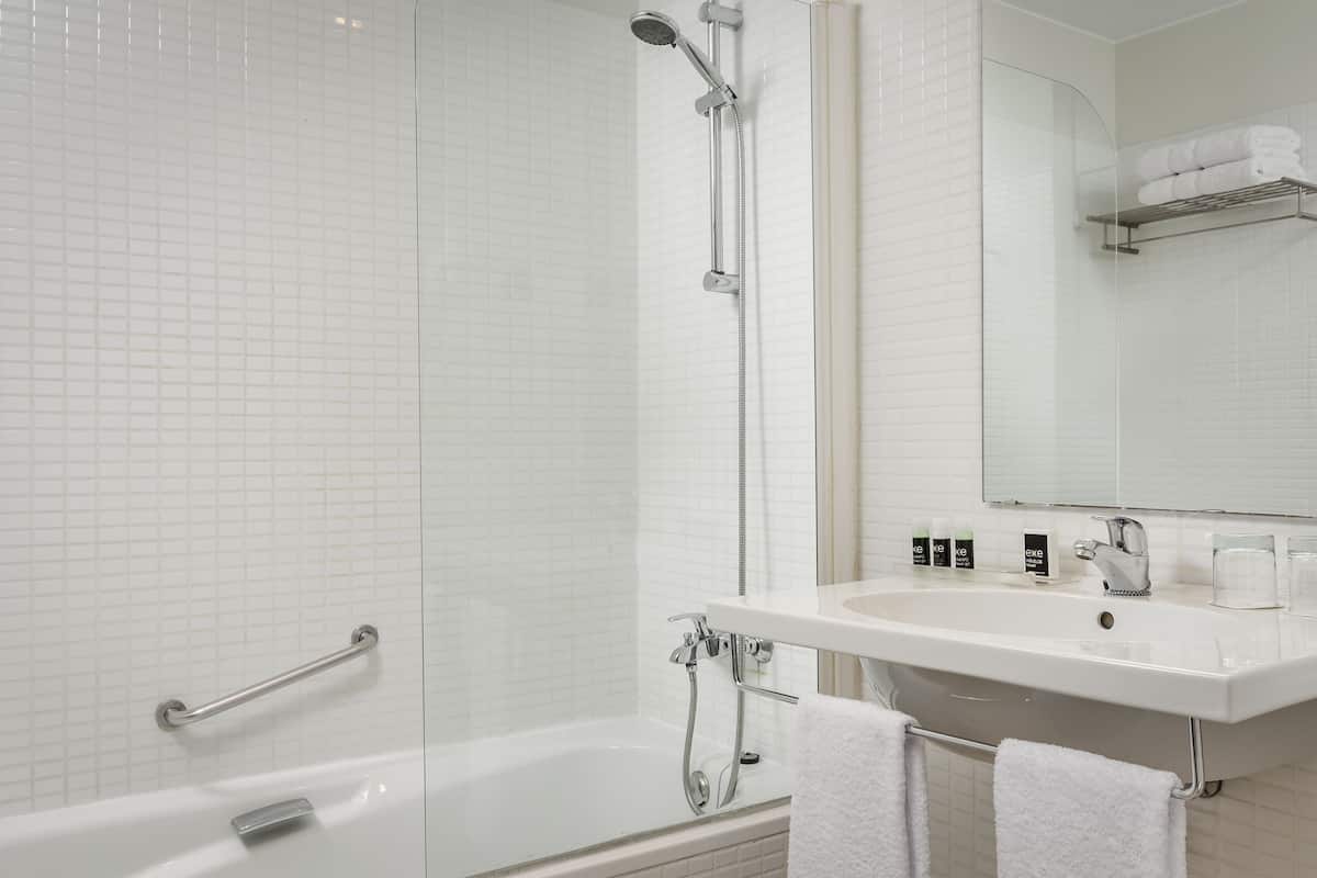 A modern bathroom with a glass-enclosed shower, a white sink, and a mirror above the sink.