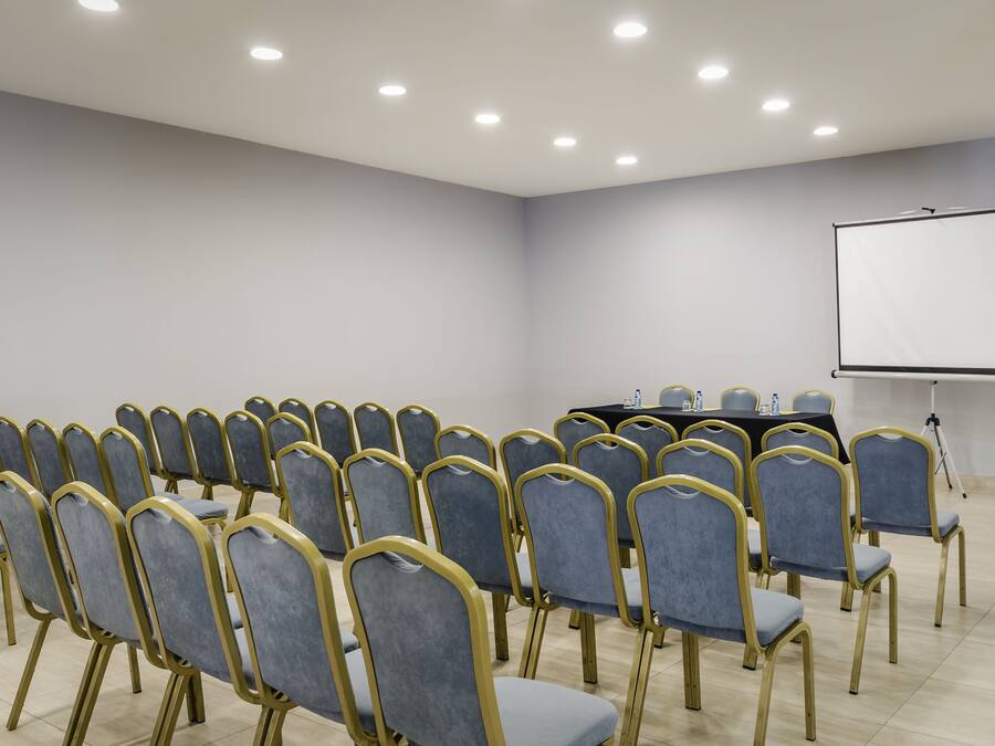 A conference room with rows of chairs, a table, and a projector screen.
