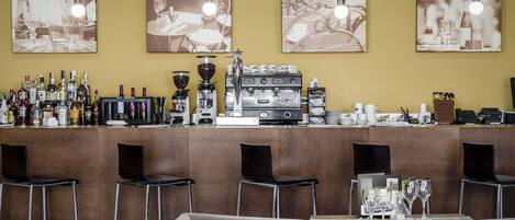 A bar area with a coffee machine, bar stools, and a table set for dining.