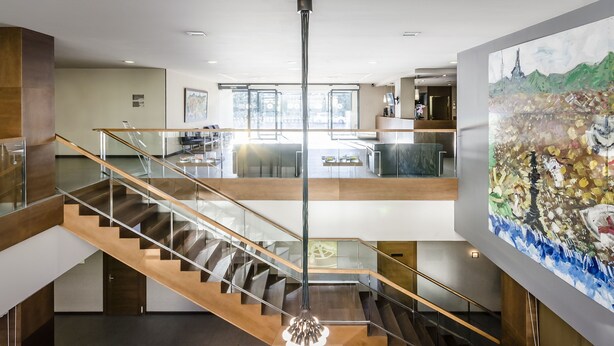 Un vestíbulo de hotel moderno con una escalera, un candelabro y un cuadro grande.