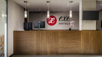 Een modern ontworpen hotel receptiebalie, met een houten toonbank, een logo en een flatscreen televisie.