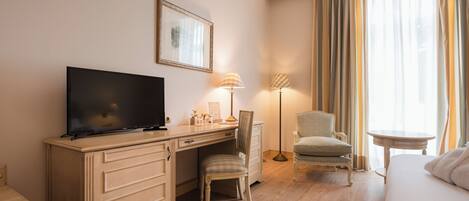Habitación de hotel con televisión de pantalla plana, escritorio, silla, mesita de noche y cama.