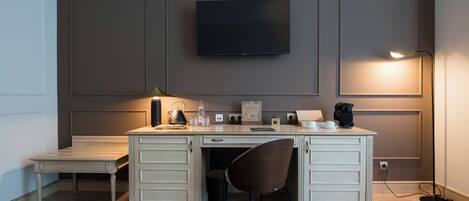 A modern office space with a desk, chair, and a mounted flat-screen TV.