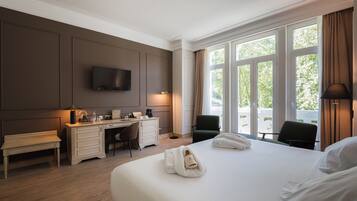 Una habitación de hotel con una cama grande, un escritorio con una silla, un televisor y una ventana con cortinas.