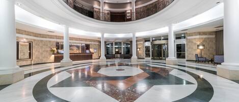 A spacious lobby with a central circular design, multiple floors, and a reception area.
