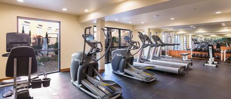 Un gimnasio con cintas de correr, elípticas y máquinas de pesas.