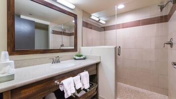 A bathroom with a wooden vanity, a large mirror, a sink, and a shower area.