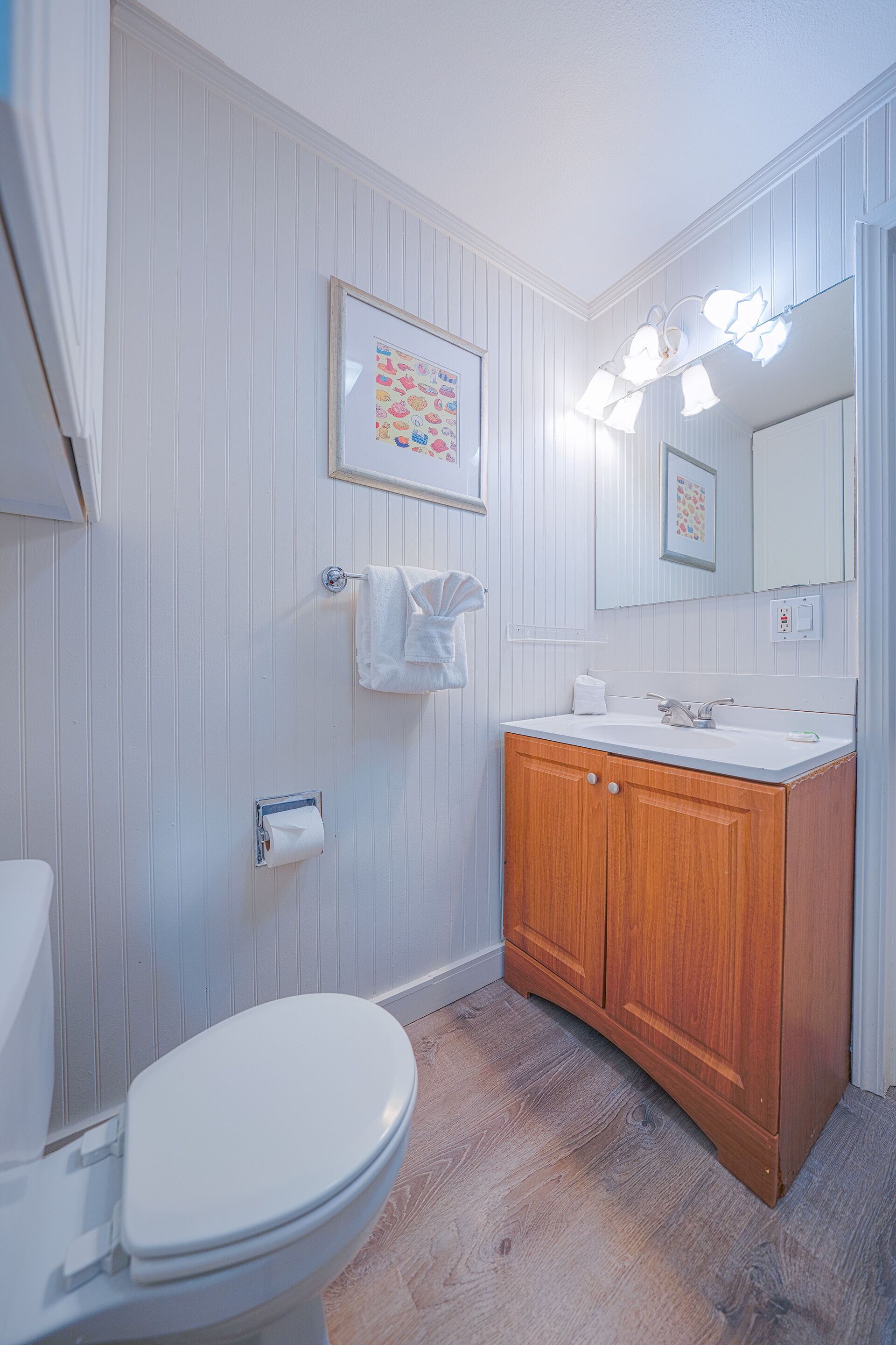 Un baño con inodoro blanco, tocador de madera y espejo con iluminación.