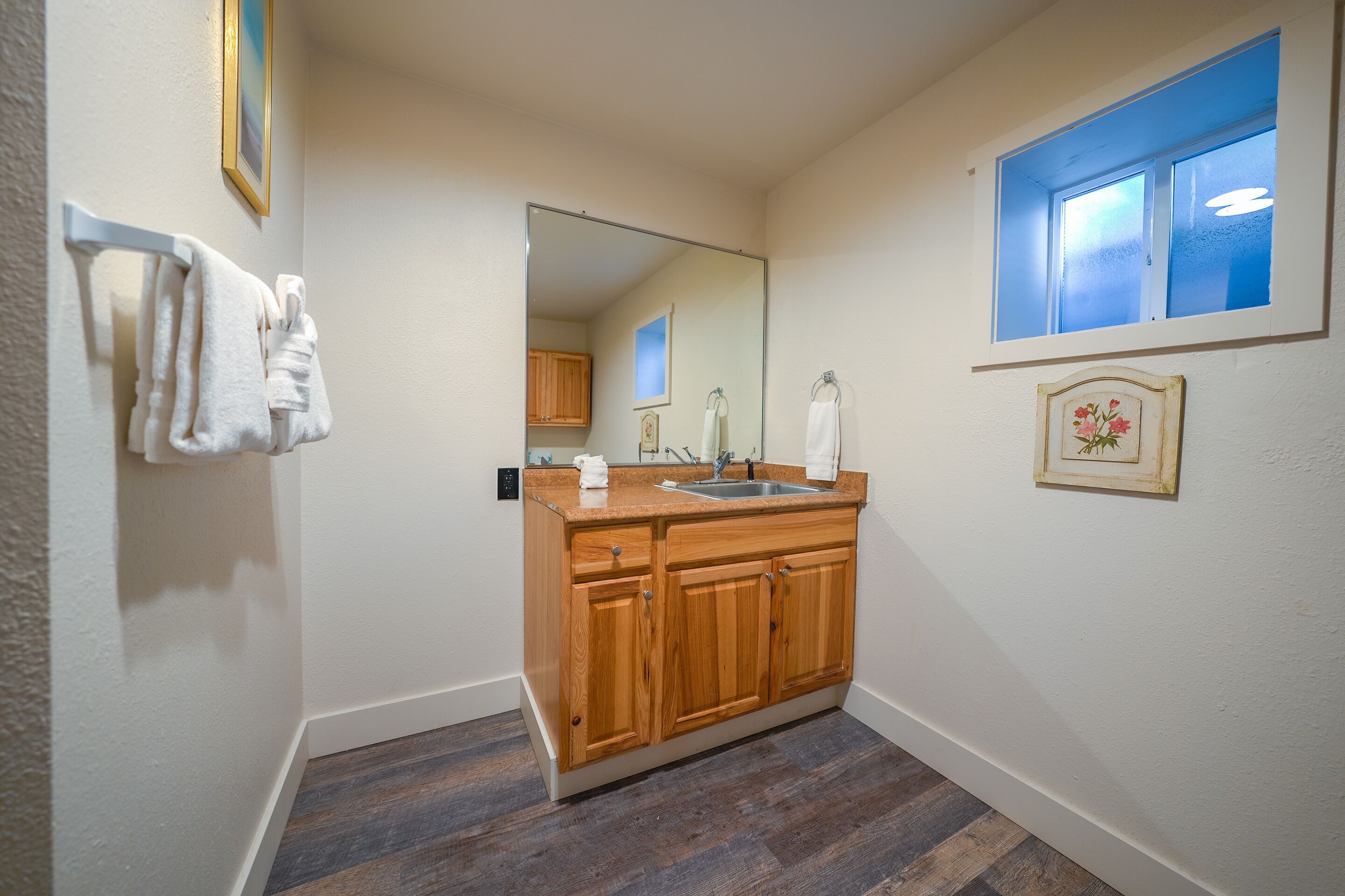 Un baño con tocador de madera, un espejo, un lavabo y un perchero para toallas.