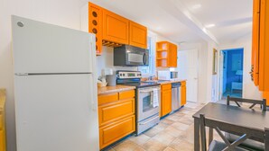 Una cocina con armarios color naranja, un refrigerador blanco, una estufa y un microondas.