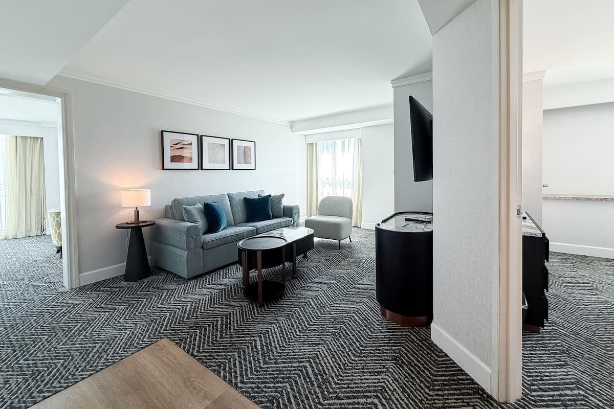 Een hotelkamer met een bank, een salontafel, een televisie en een kamerbreed tapijt met dessin.