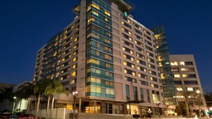 Un hotel de varios pisos con un diseño moderno, destacando un letrero grande que dice 'Embassy Suites'.