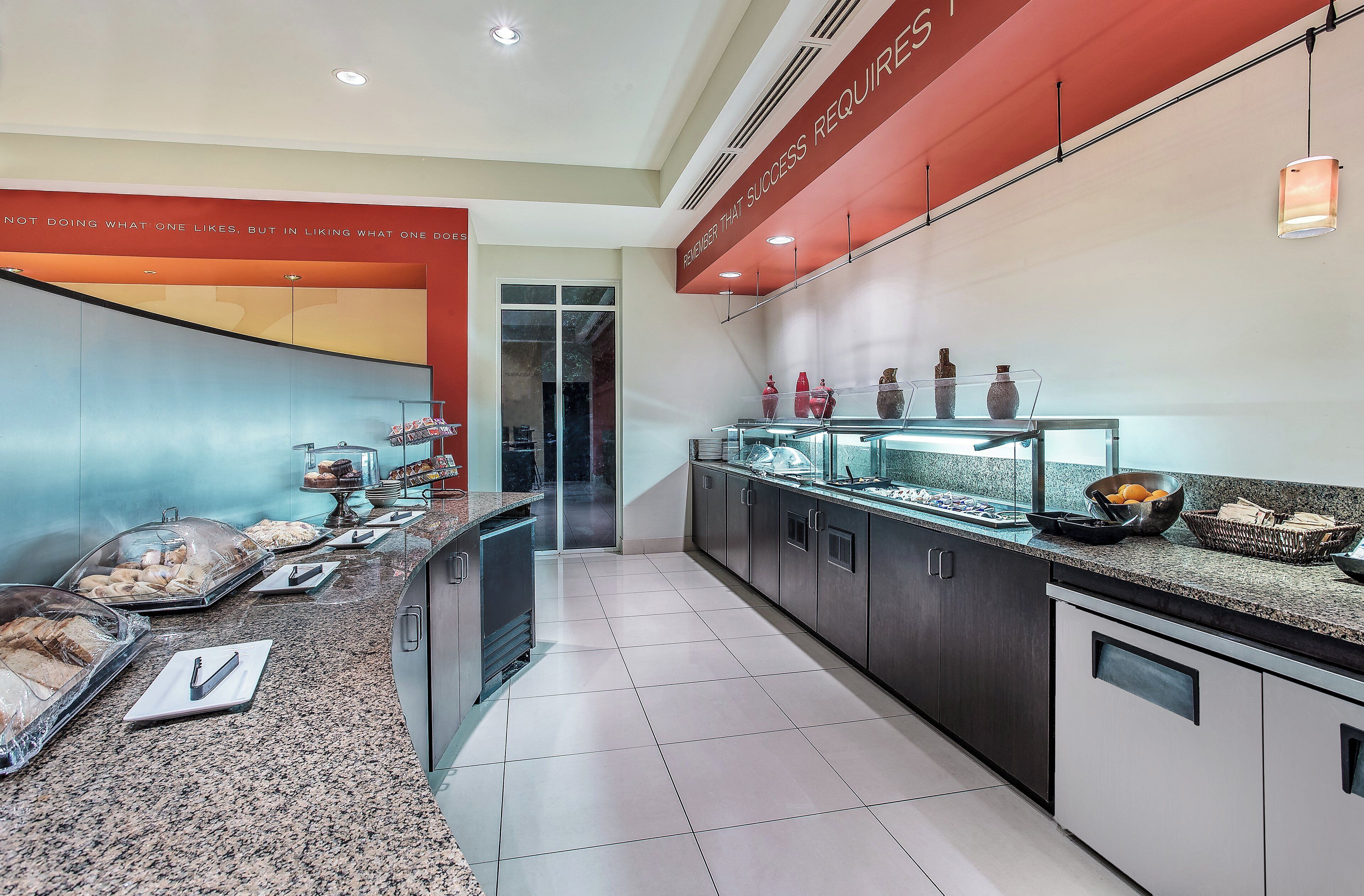 Una cocina moderna con encimeras de granito, una vitrina de vidrio con objetos decorativos y una pared de acento roja.