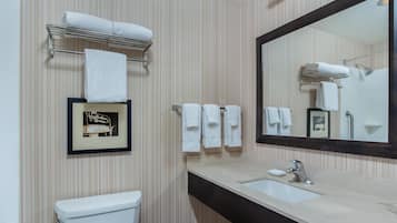 A bathroom with striped wallpaper, a toilet, a sink with a mirror, and multiple towels on a rack.