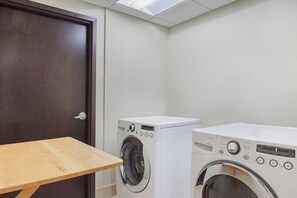 Un lavadero con dos lavadoras, una mesa de madera y una puerta.