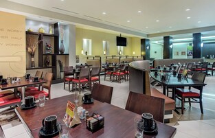 Un restaurante moderno con varias mesas y cabinas, equipado con cafeteras y recipientes para condimentos.