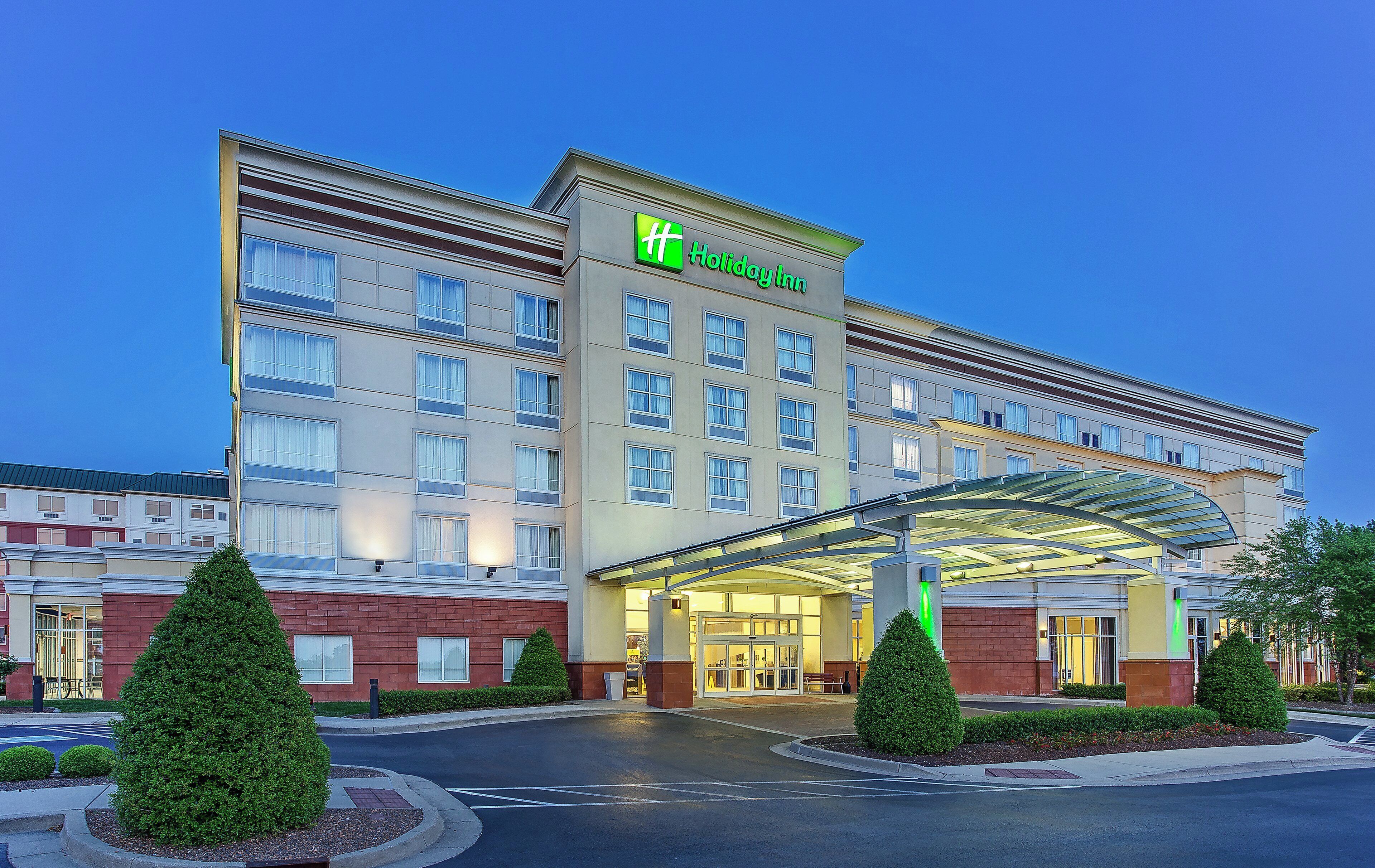 Un hotel Holiday Inn con fachada moderna, varios pisos y entrada cubierta.