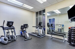 Un gimnasio con bicicletas estáticas, cintas de correr y una banca para pesas.