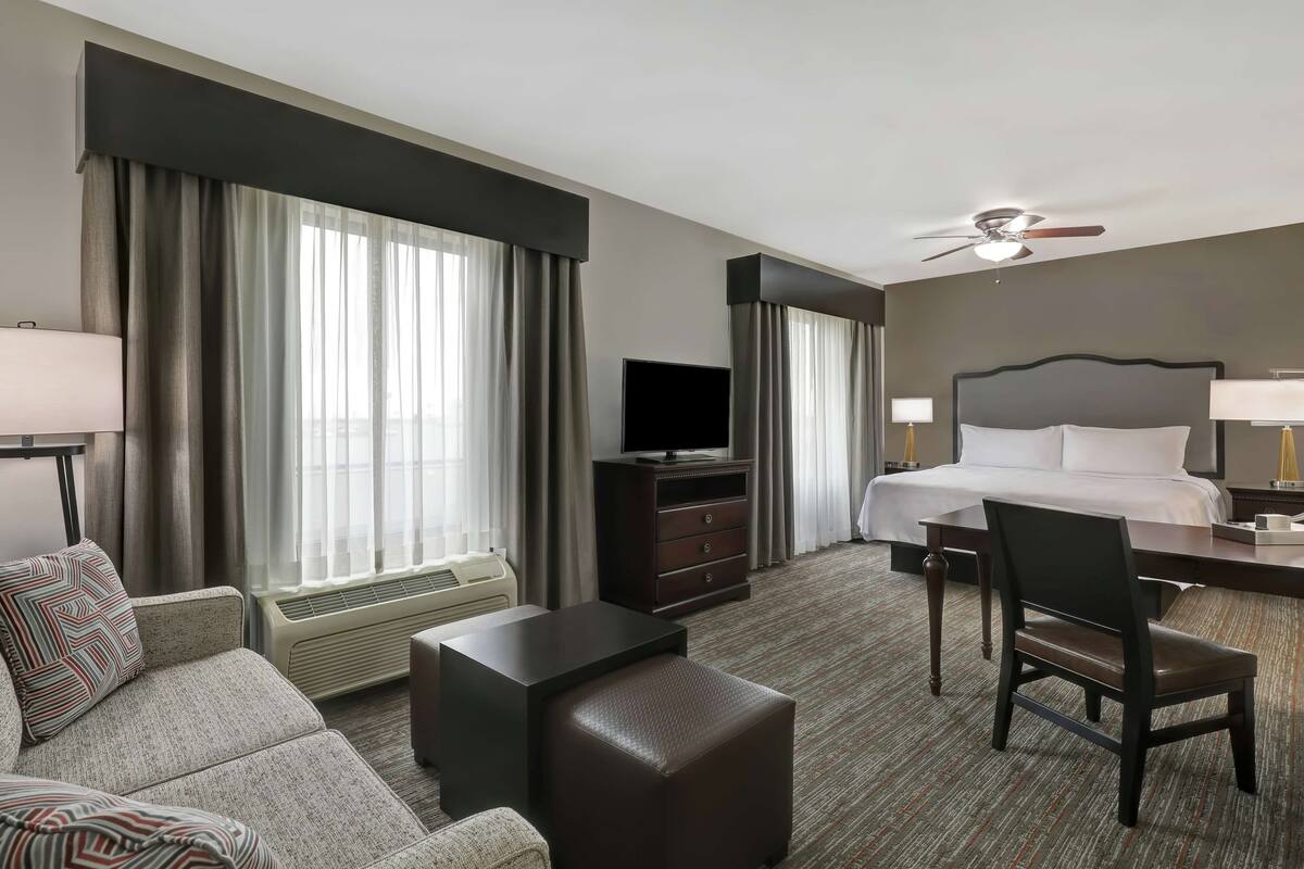 Una habitación de hotel con cama, televisión, escritorio, silla y sofá.