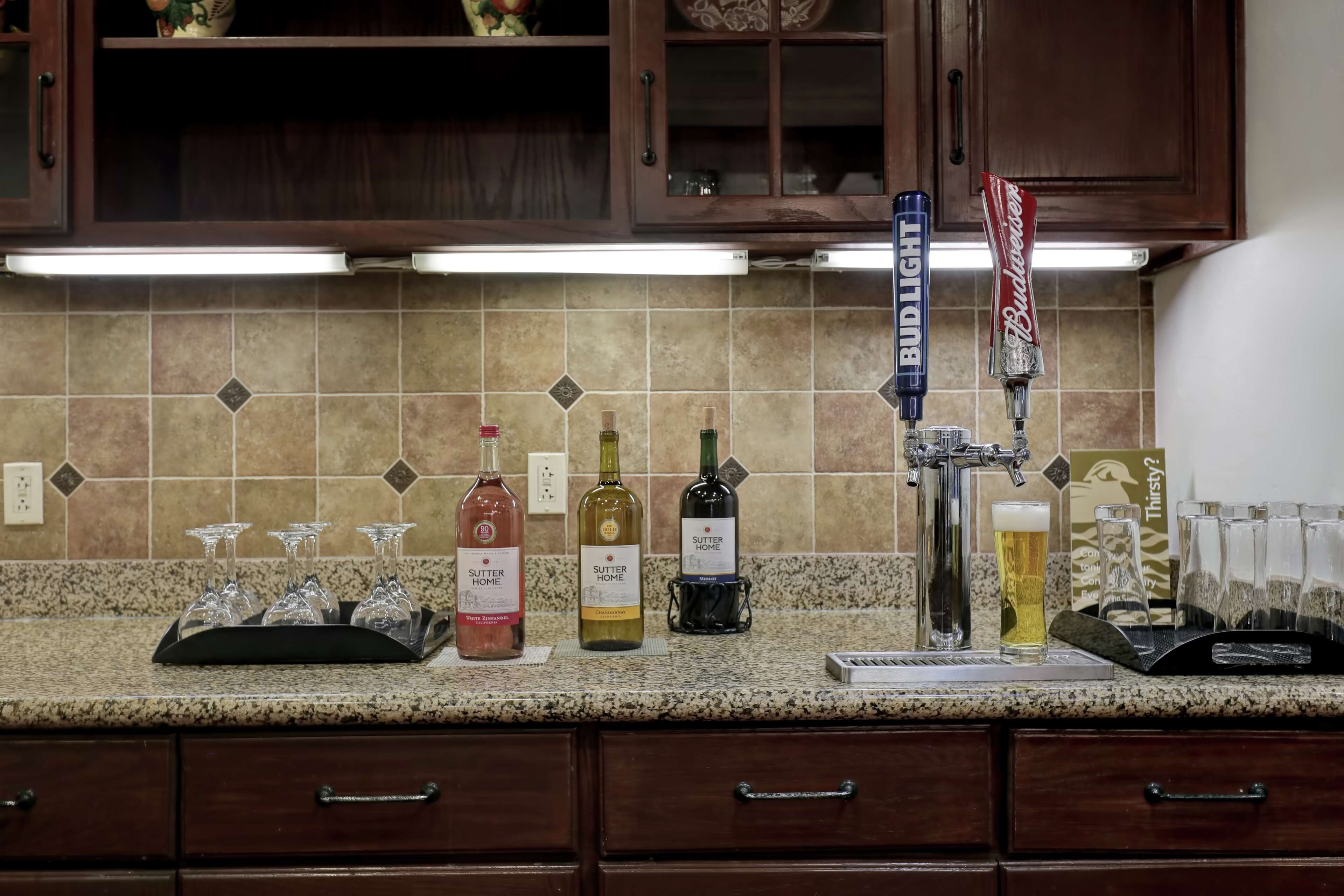 A kitchen counter with a beer tap, wine bottles, and glasses.