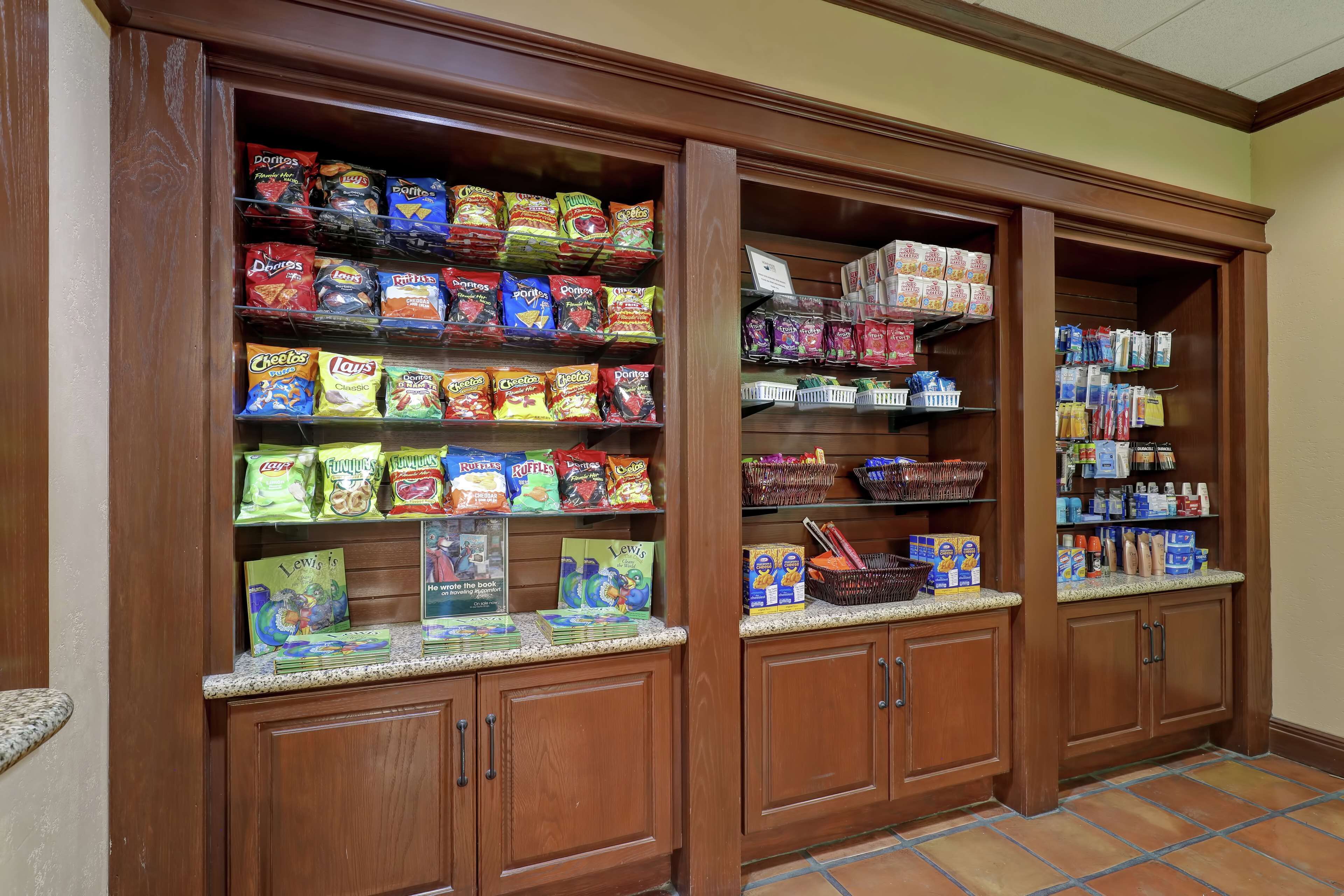 A snack and book display in a wooden cabinet with multiple shelves.