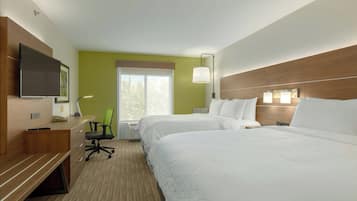 A hotel room with two beds, a desk, a chair, a television, and a window.
