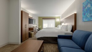 A hotel room with a bed, a blue sofa, a desk with a chair, a TV, and a window with curtains. - Holiday Inn Express Hotel & Suites Vestal by IHG (Vestal)
