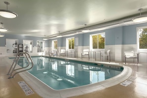 An indoor swimming pool with clear water, surrounded by white chairs and tables, and large windows allowing natural light. - Holiday Inn Express Hotel & Suites Vestal by IHG (Vestal)