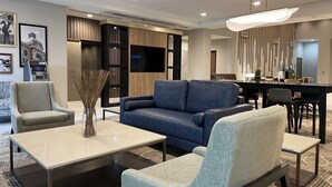 A modern living room with a sofa, armchairs, a coffee table, and a dining area with a table and chairs.