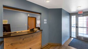 A reception area with a wooden counter, a door, and an exit sign. - Extended Stay America Select Suites - Denver - Aurora (Aurora)