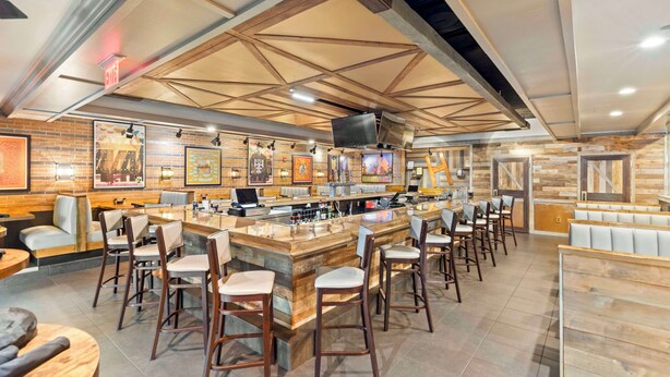 A restaurant interior with a bar area, seating, and artwork on the walls. - DoubleTree by Hilton Front Royal Blue Ridge Shadows (Front Royal)