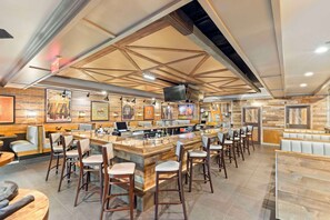 A restaurant interior with a bar area, seating, and artwork on the walls. - DoubleTree by Hilton Front Royal Blue Ridge Shadows (Front Royal)