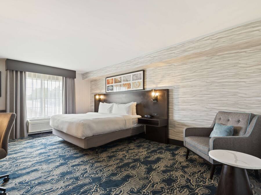 Een hotelkamer met een groot bed, een bureau, een stoel en een klein tafeltje.
